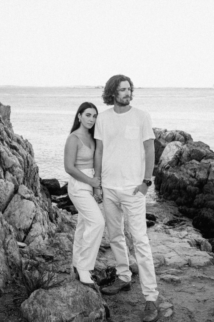 Man and woman posing on the coast in Maine wearing white outfits.