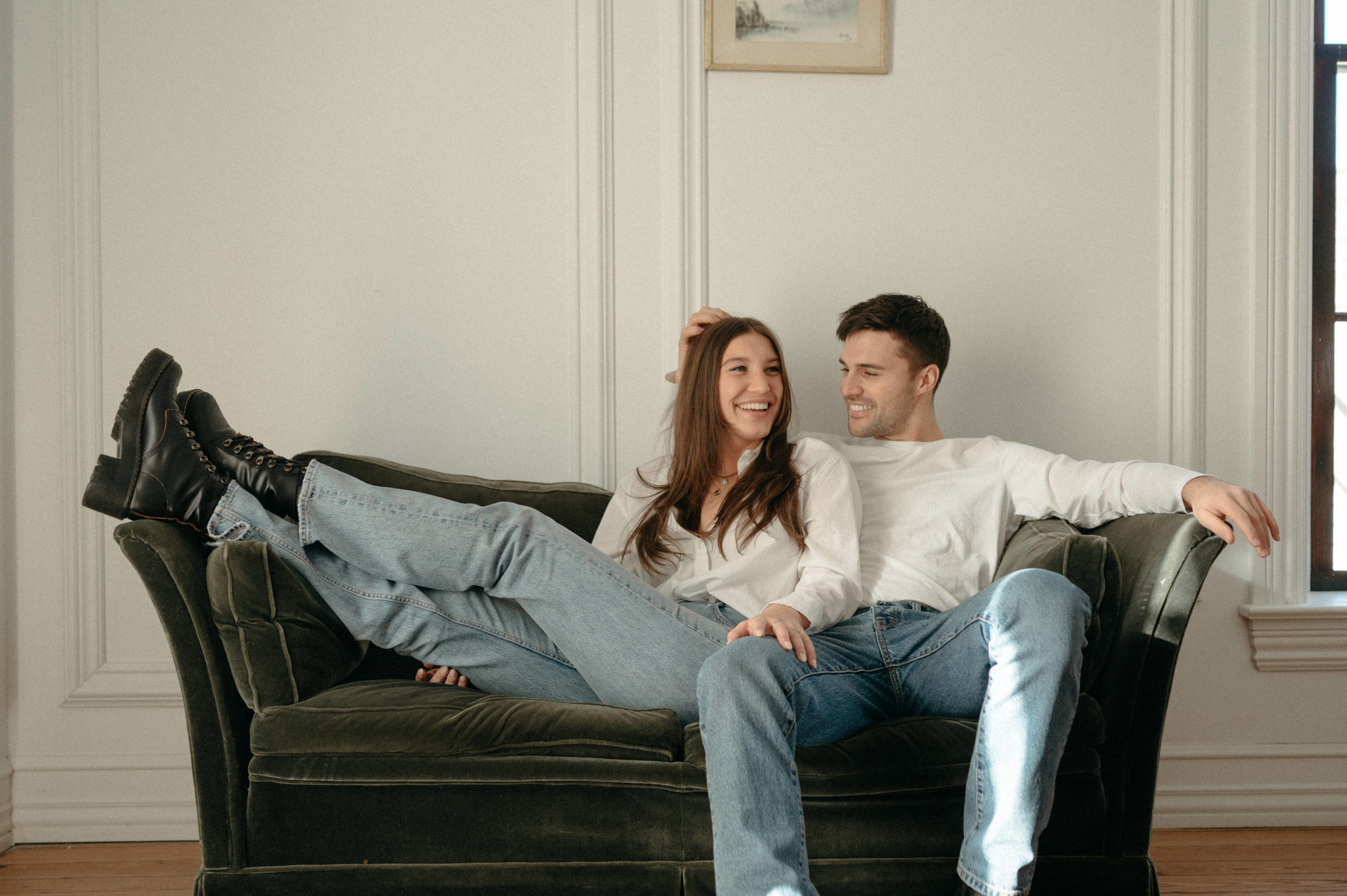 couple lounging out couch in blue jeans and white shirts
