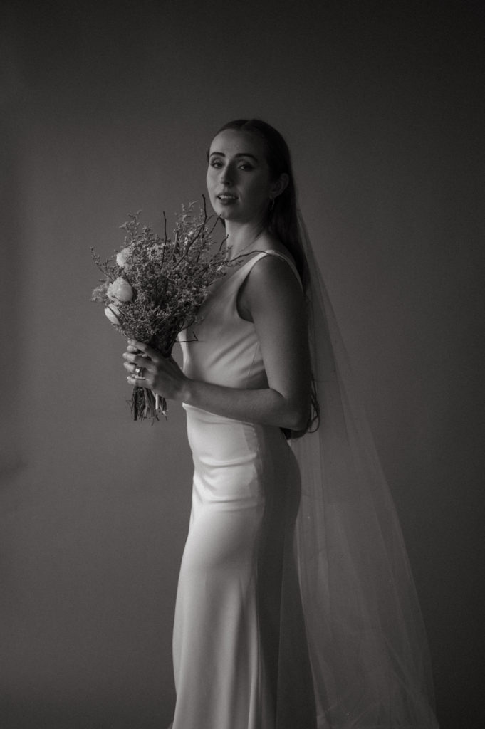 Editorial bride posing in front of backdrop in black and white 