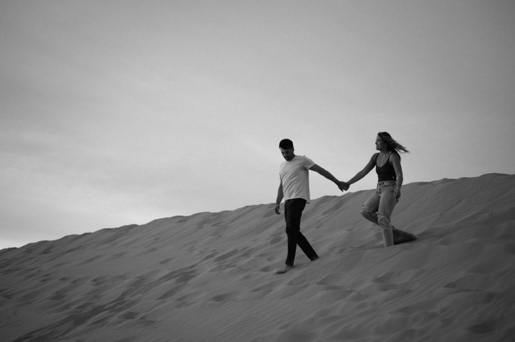 Couple running down sand dunes in southern California  