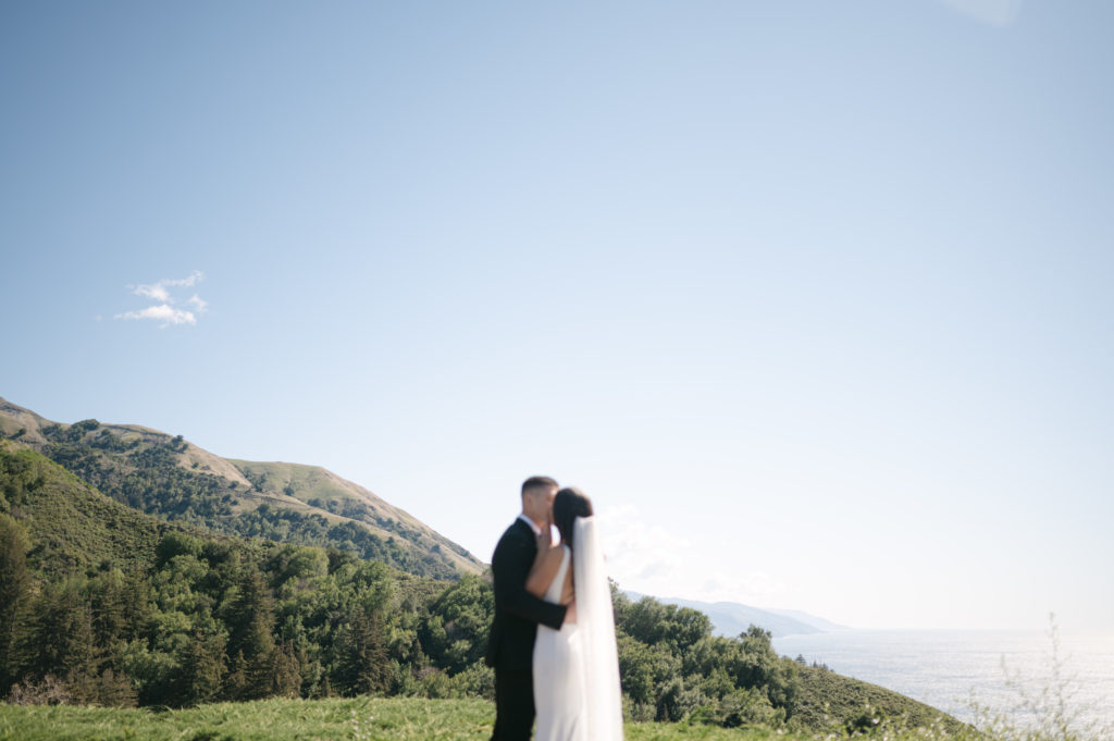 Couple kissing at an overlook in front of the view at Ventana Big Sur 