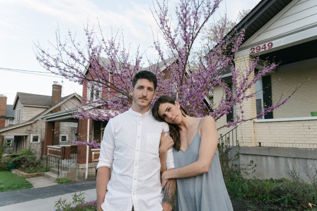 Couple posing in front of blooming tree in Cincinnati 
