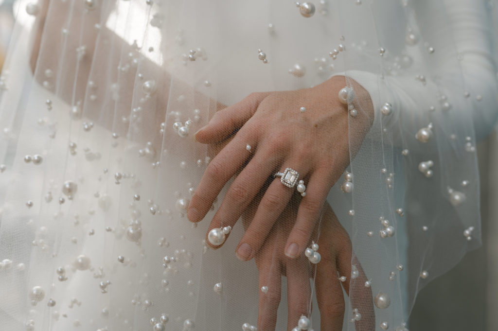 Detail shot of brides engagement ring and pearl veil. 