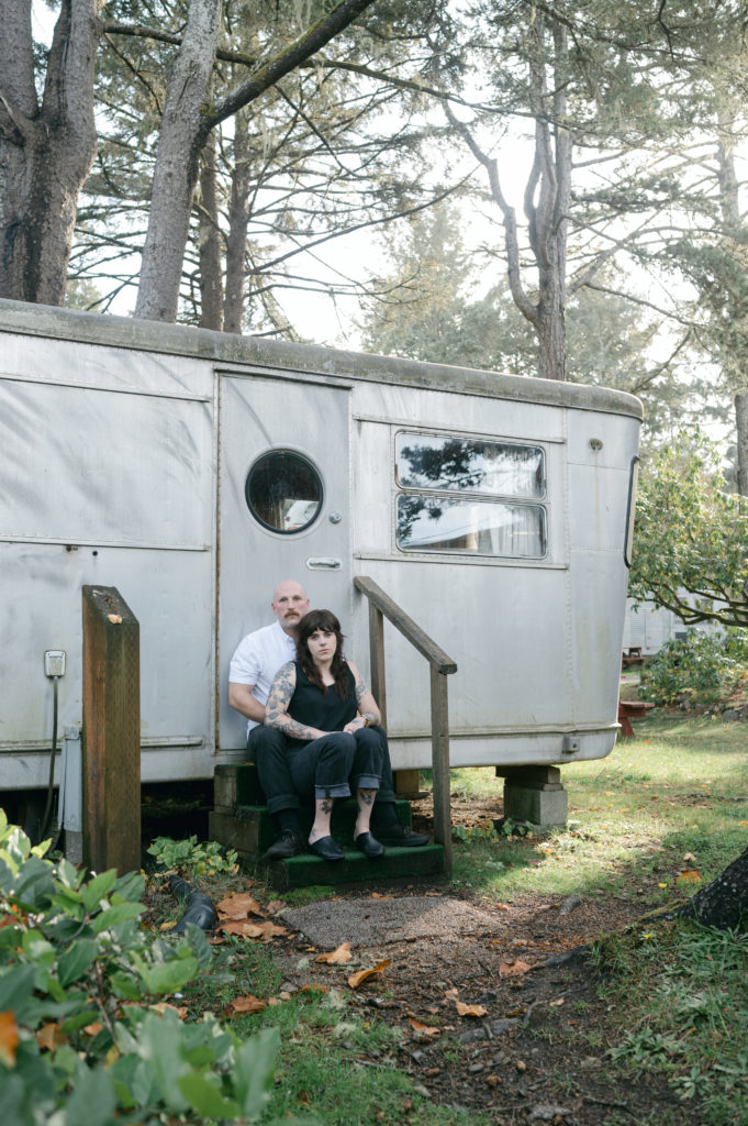 Couple sitting in front of vintage camper in Seaview, Washington