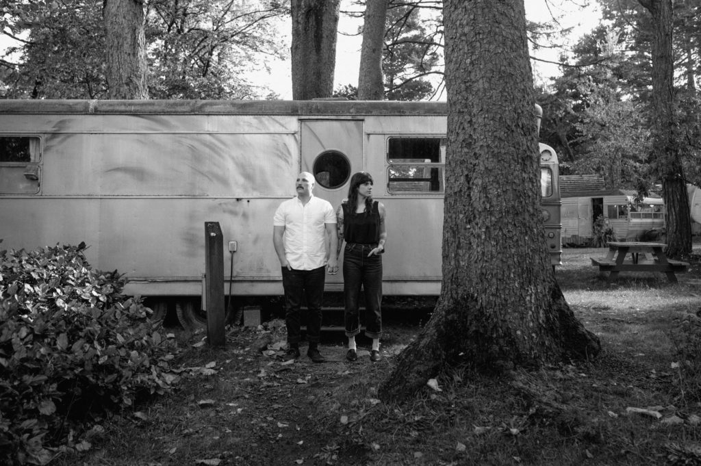 Couple posing in front of vintage camper in Seaview, Washington
