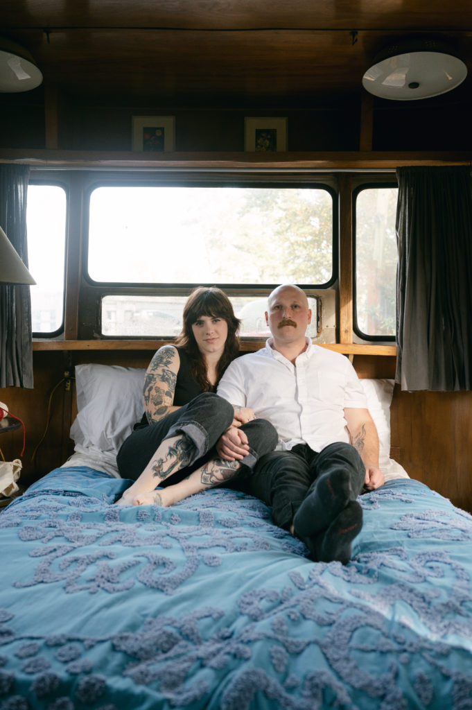 Couple snuggled up in bed in vintage camper in Sou'wester lodge in Seaview