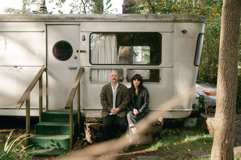 Couple sitting in front of vintage camper in Sou'wester lodge in Seaview