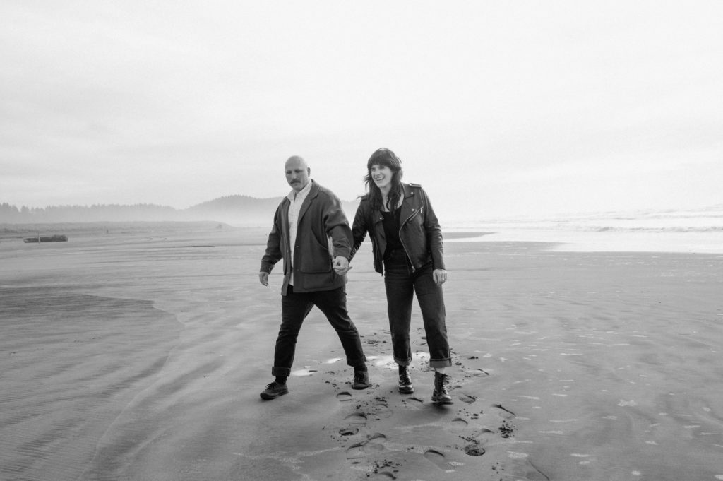 Black and white image of couple walking down the beach in Washington
