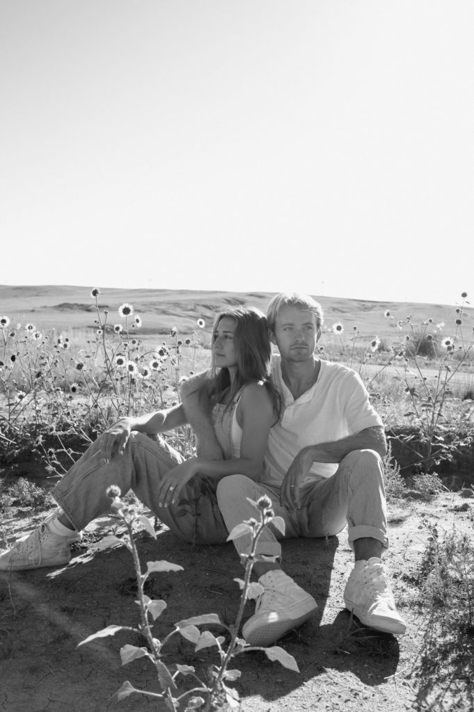 Black and white portrait of a couple sitting in front of sunflowers 