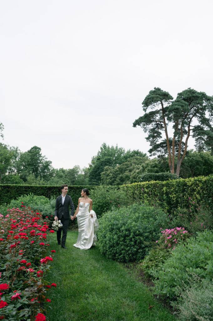 Luxury bride and groom walking through rose garden at Pinecroft Mansion in Cincinnati, Ohio.