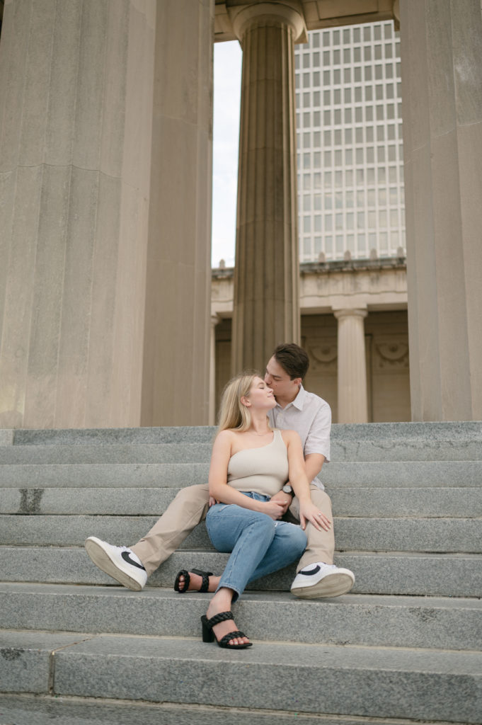 Future bride and groom sitting on the stairs in front of The War Memorial Building for their engagement photos in Nashville, Tennessee 