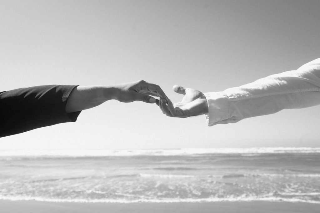 Black and white image of couples hands at Cannon Beach in Oregon 