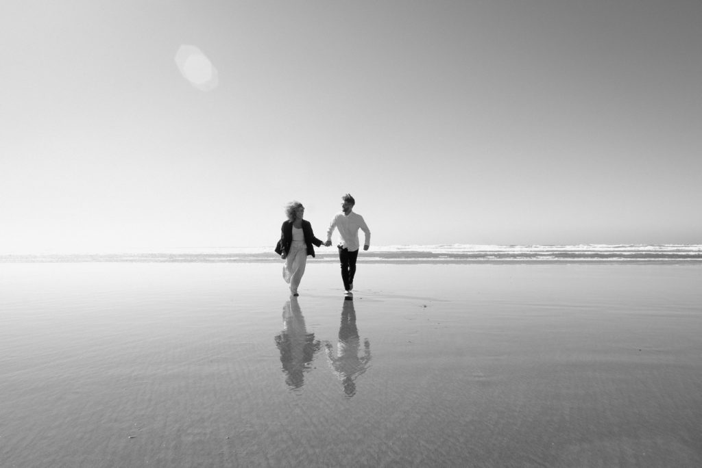 Couple running on the beach at the Oregon Coast 