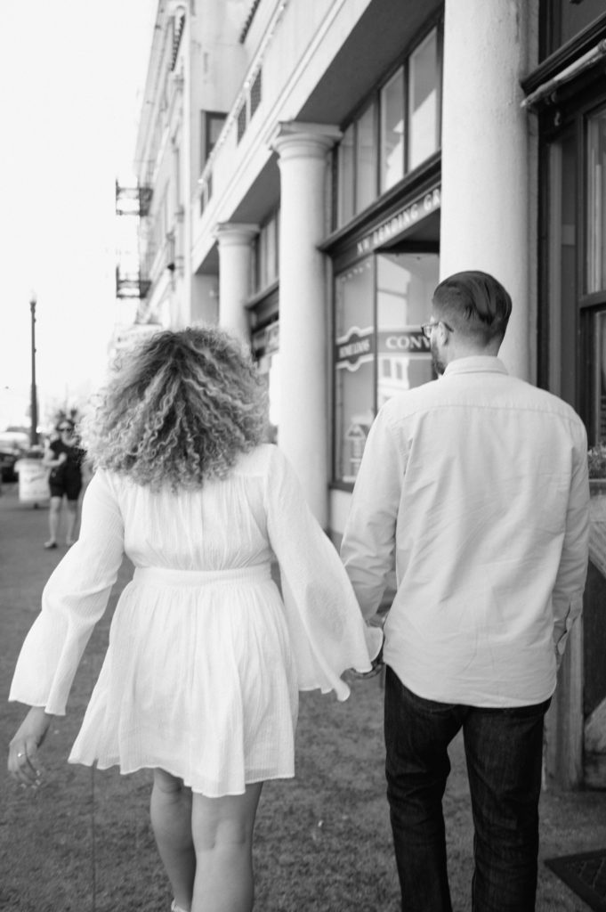 Black and white image of couple walking down the streets in Astoria, Oregon