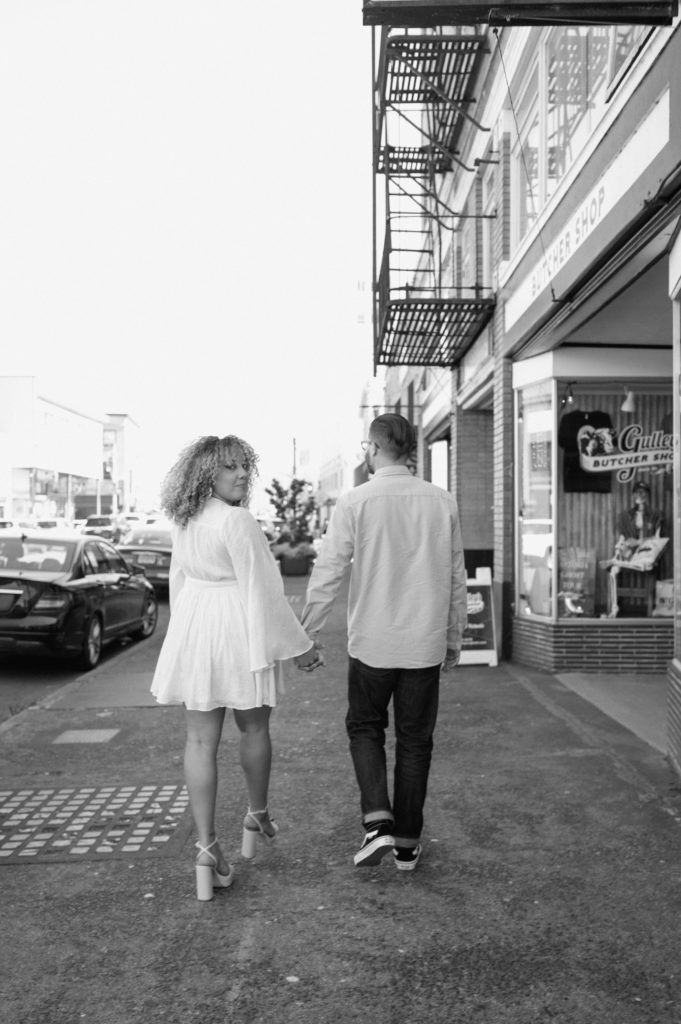 Black and white image of couple walking down the street in Astoria, Oregon