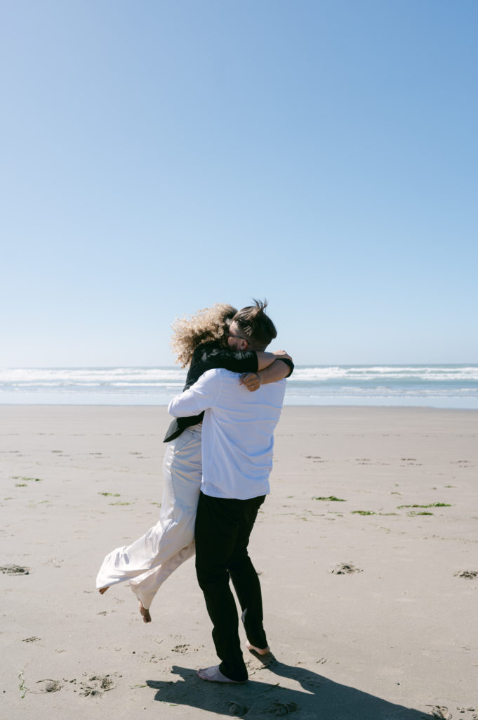 Bride being spun around by her fiancé on Cannon Beach 