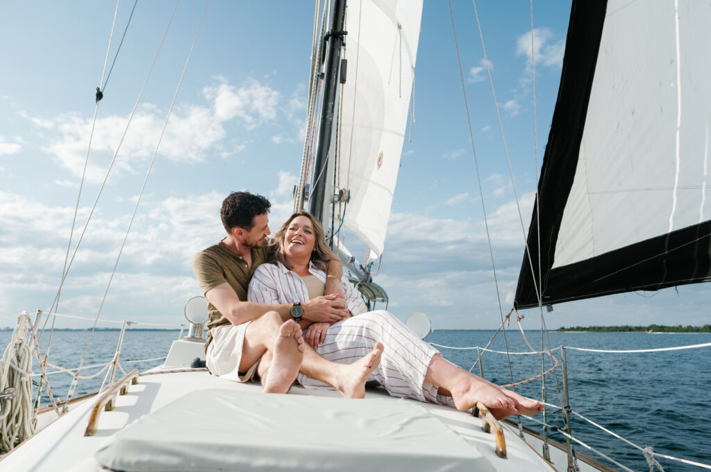 Couple sitting on the front of their sailboat for engagement photos in Florida 