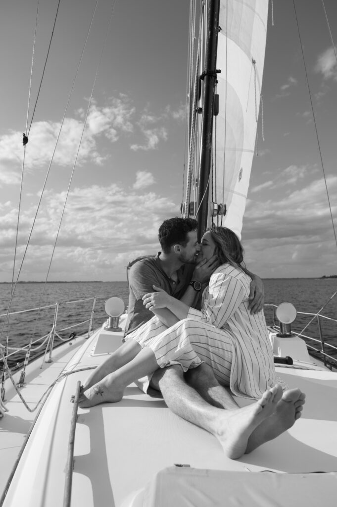 Couple kissing on the front of a sailboat for engagement photos 