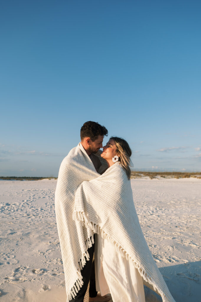 Couple snuggled in a blanket on Shell Island in Florida 