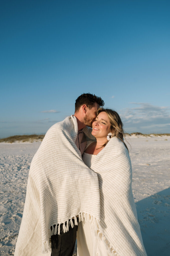 Couple snuggled in a blanket on Shell Island in Florida 