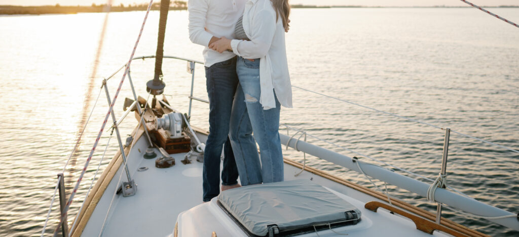 Couple posing on the bow of the Sailboat at golden hour