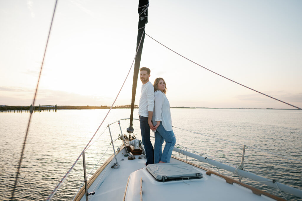 Couple posing on the bow of the Sailboat at golden hour