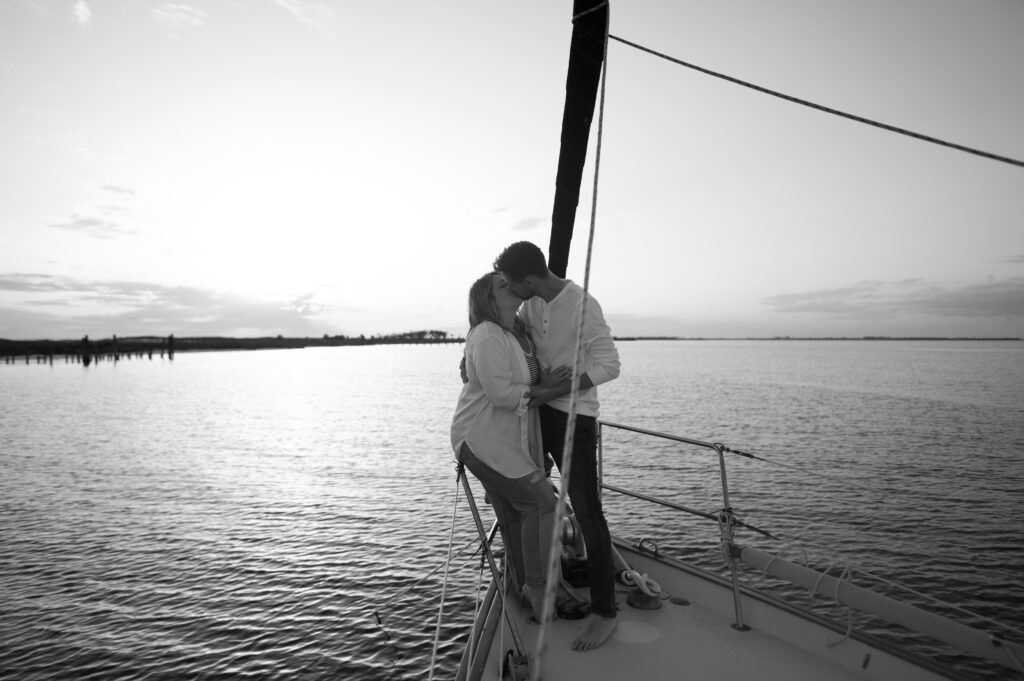 Couple kissing on the bow of the Sailboat at golden hour