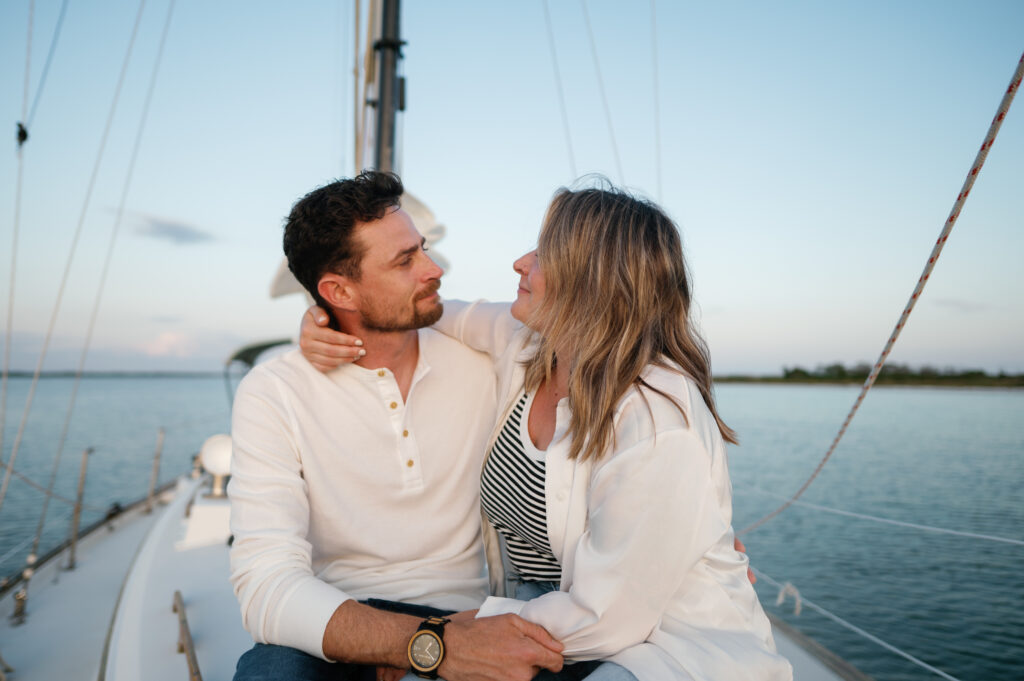 Couple snuggling on the bow of the Sailboat at golden hour