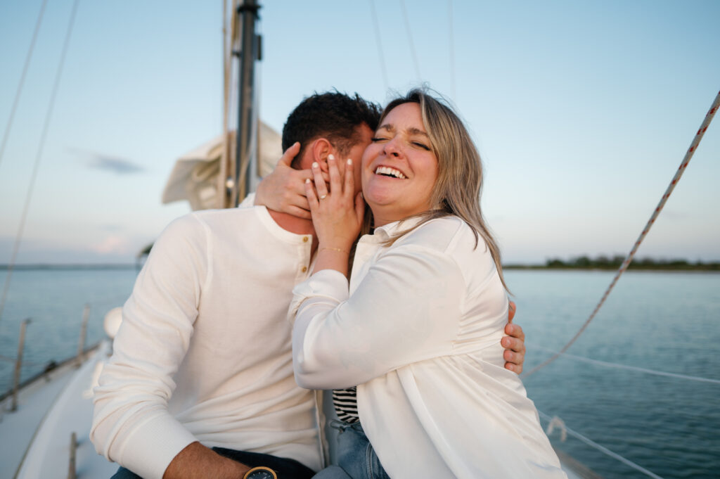 Couple snuggling on the bow of the Sailboat at golden hour