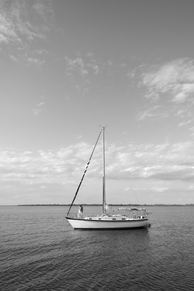 Black and white image of couple kissing on their sailboat 