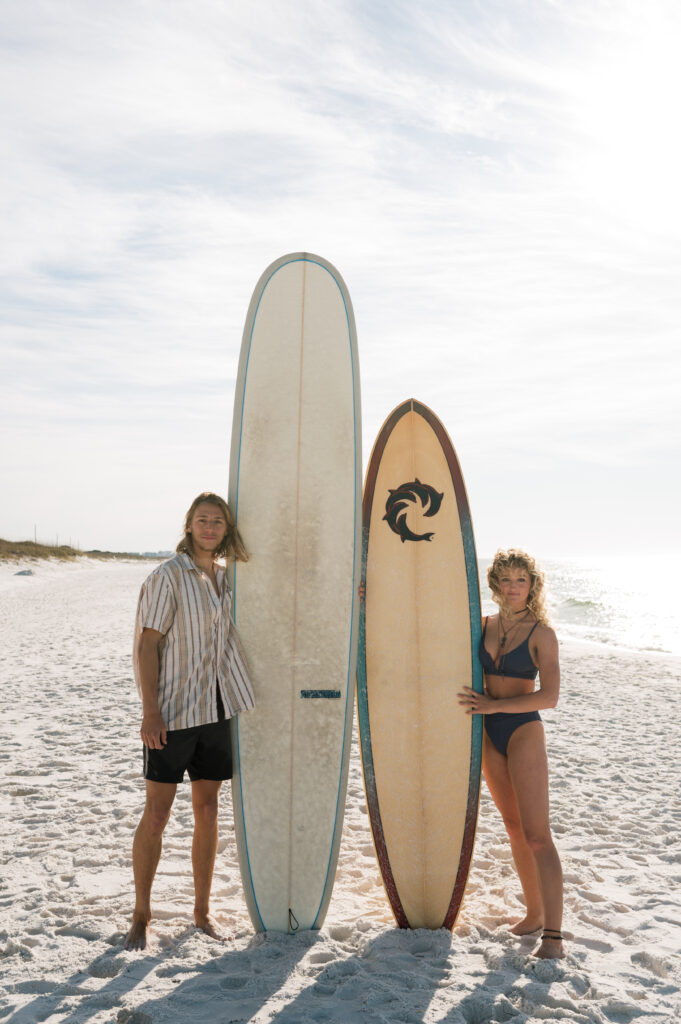 Couple posing with their surfboards at sunrise 