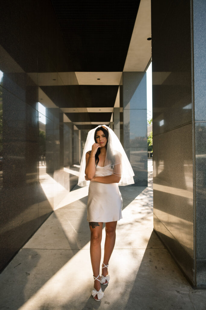 Bride wearing short white slip dress and vintage veil for engagement photos in Downtown Cincinnati 