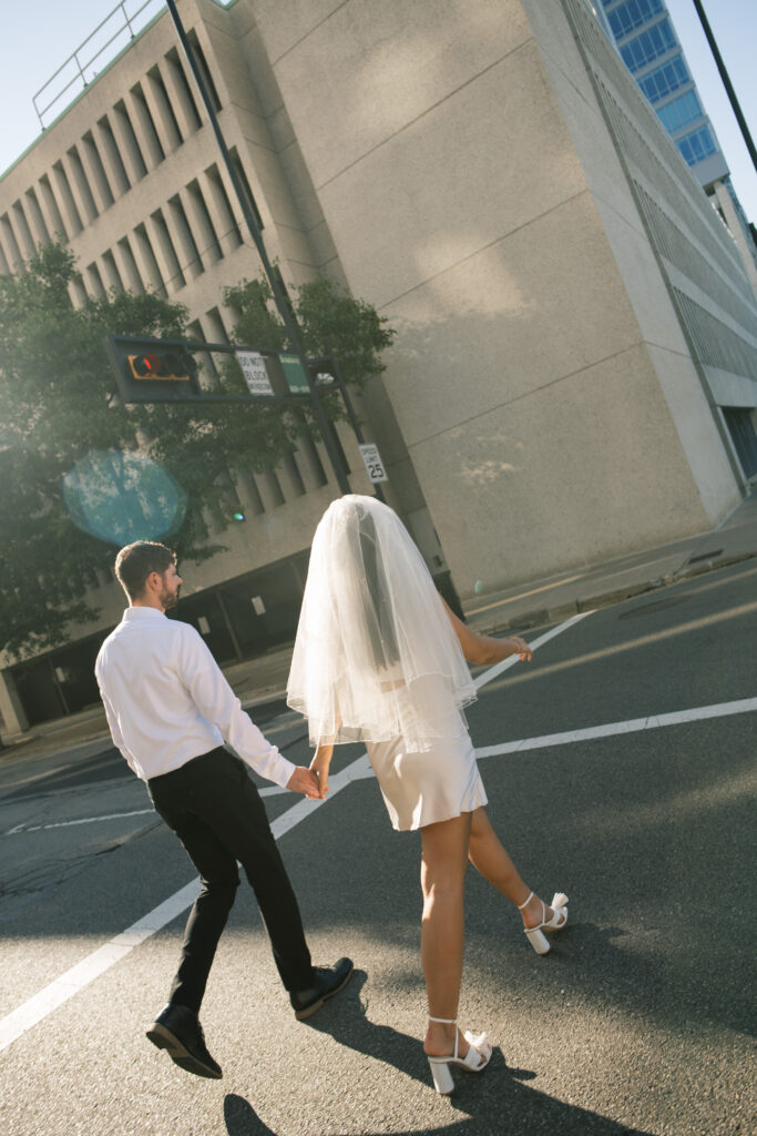 Couple walking across the street in Downtown Cincinnati, OH for engagement photos 