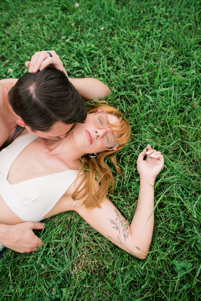 Editorial pose of couple laying in the grass