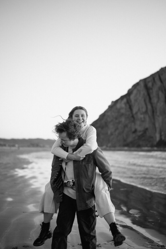 black and white image of couple running on the beach in california 