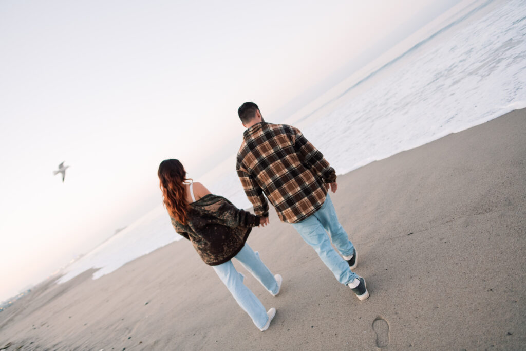 Couple holding hands and walking on the beach in Santa Monica 