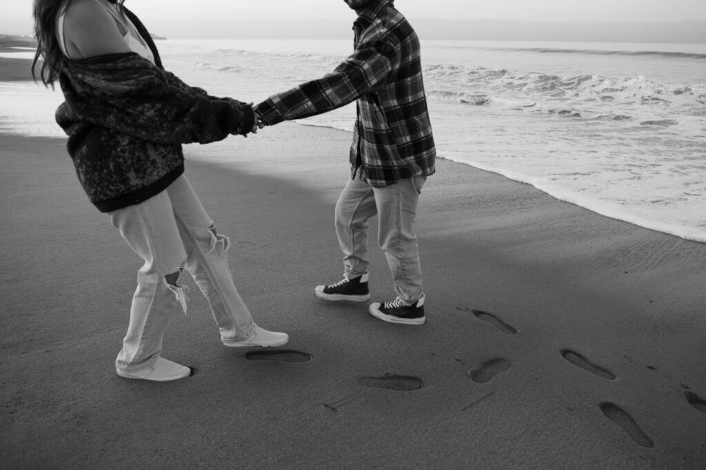 Couple holding hands and walking on the beach in Santa Monica 