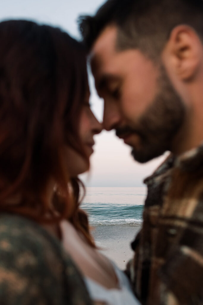 A photo with the ocean in focus shot between the couple 