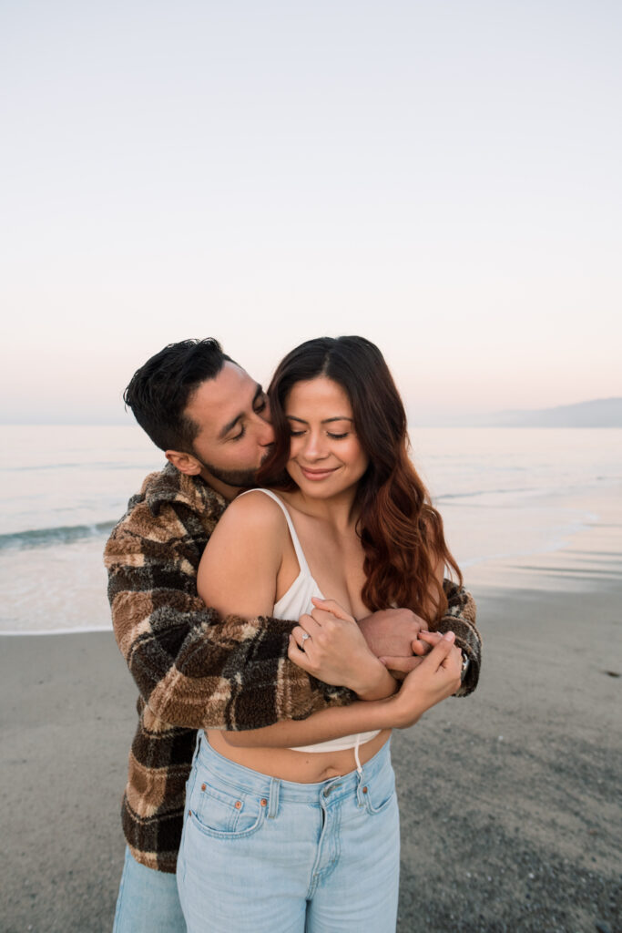 Couple snuggled up on the beach at sunrise in california 