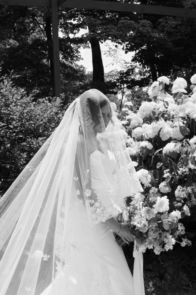 Bride posing in front of a hydrangea bush during her summertime wedding in Cincinnati, Ohio