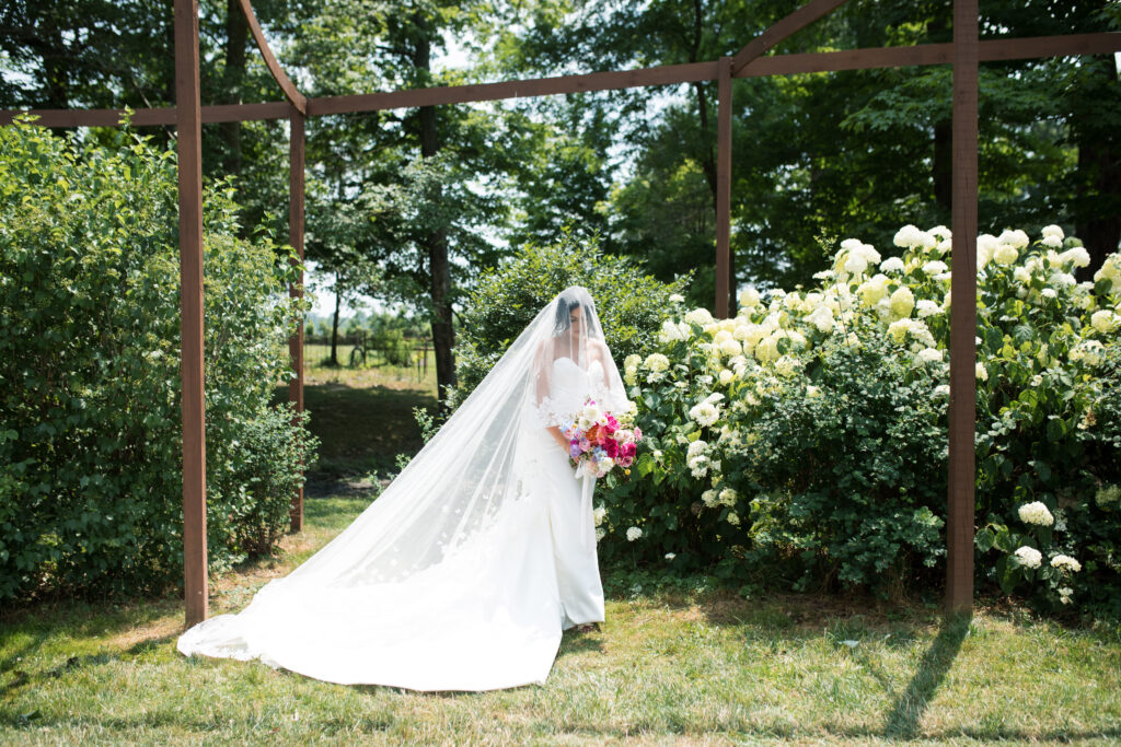 Bride posing in front of a hydrangea bush during her summertime wedding in Cincinnati, Ohio