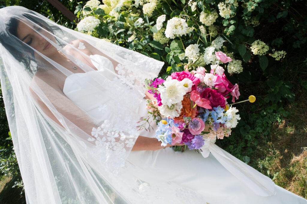 Bride posing in front of a hydrangea bush during her summertime wedding in Cincinnati, Ohio