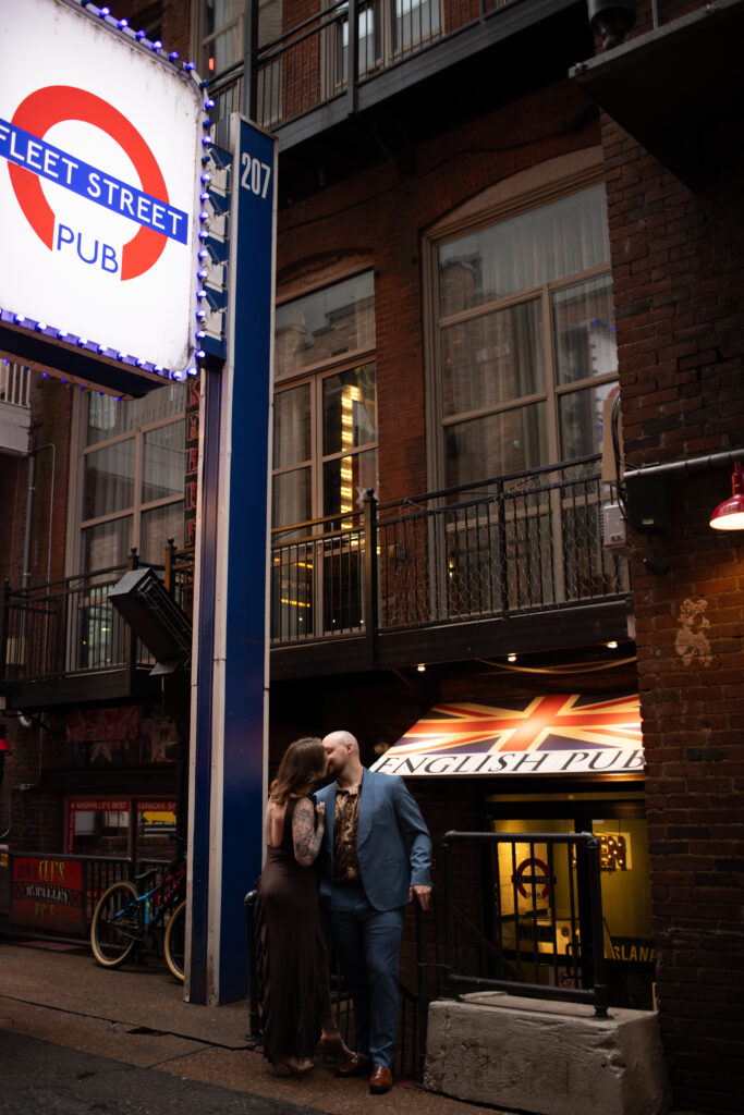 A couple kissing, underneath a neon sign in Printer's Alley 