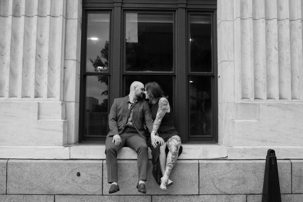 A black and white image of a couple sitting in a window sill in Printer's Alley