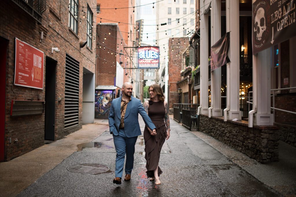 A couple walking towards me in the middle of Printer's Alley in Nashville, Tennessee 