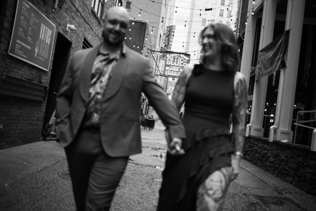 A black and white photo of a couple walking towards me in the middle of Printer's Alley in Nashville, Tennessee 