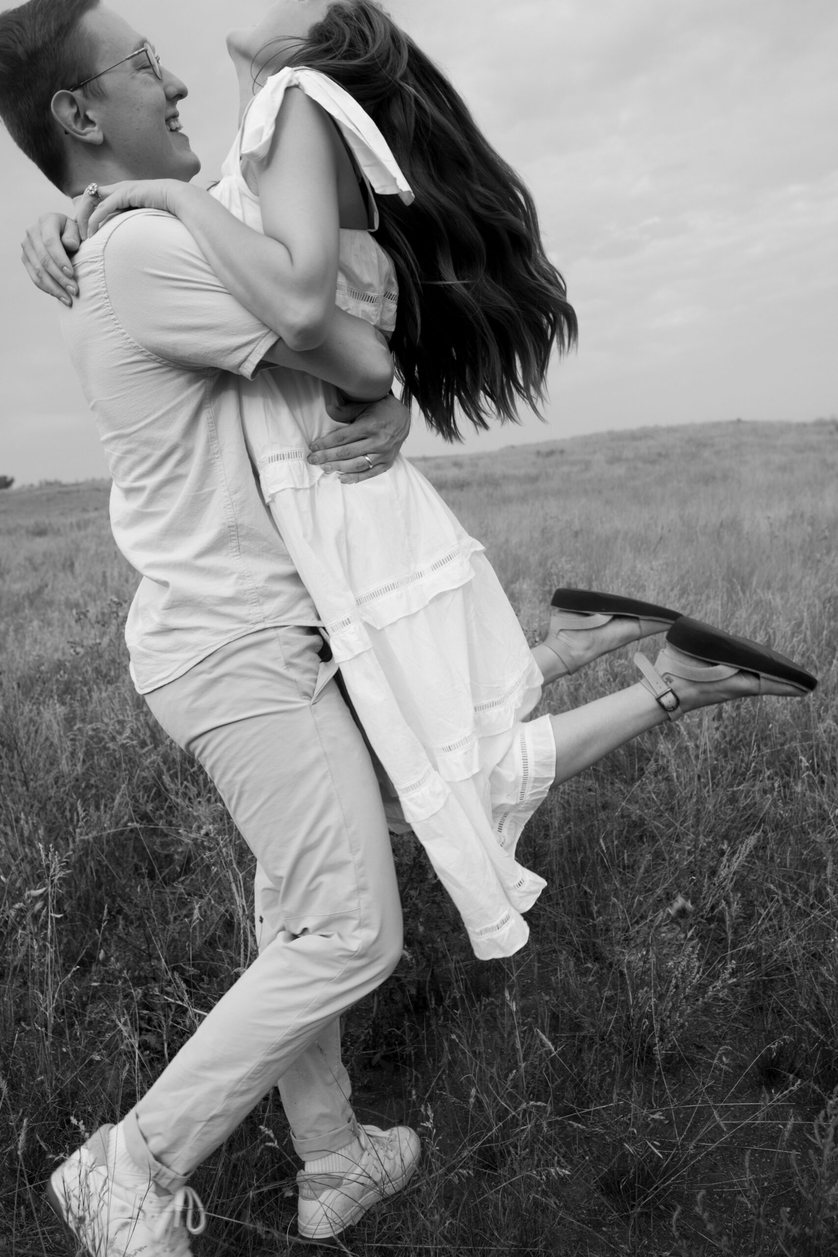 Black and white image of couple spinning around in a field