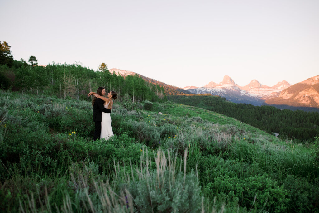 Couple posing at golden hour with Grand Teton National Park in the distance