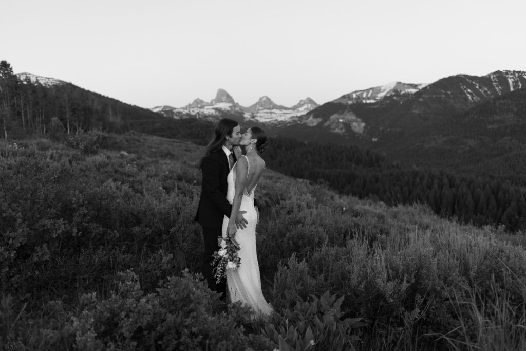 Couple posing at golden hour with Grand Teton National Park in the distance