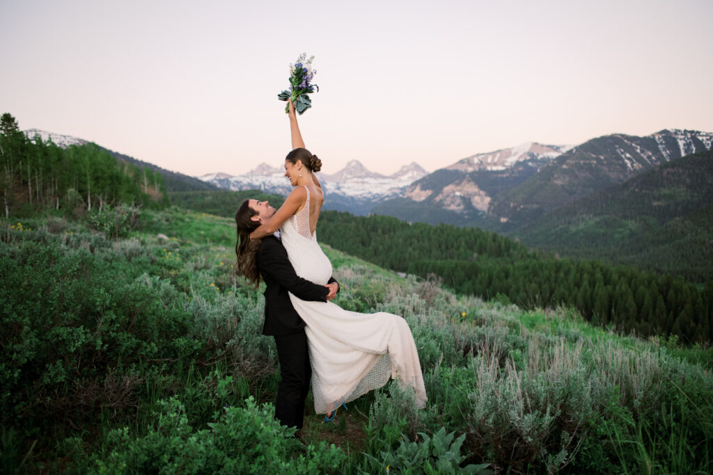 Couple posing at golden hour with Grand Teton National Park in the distance